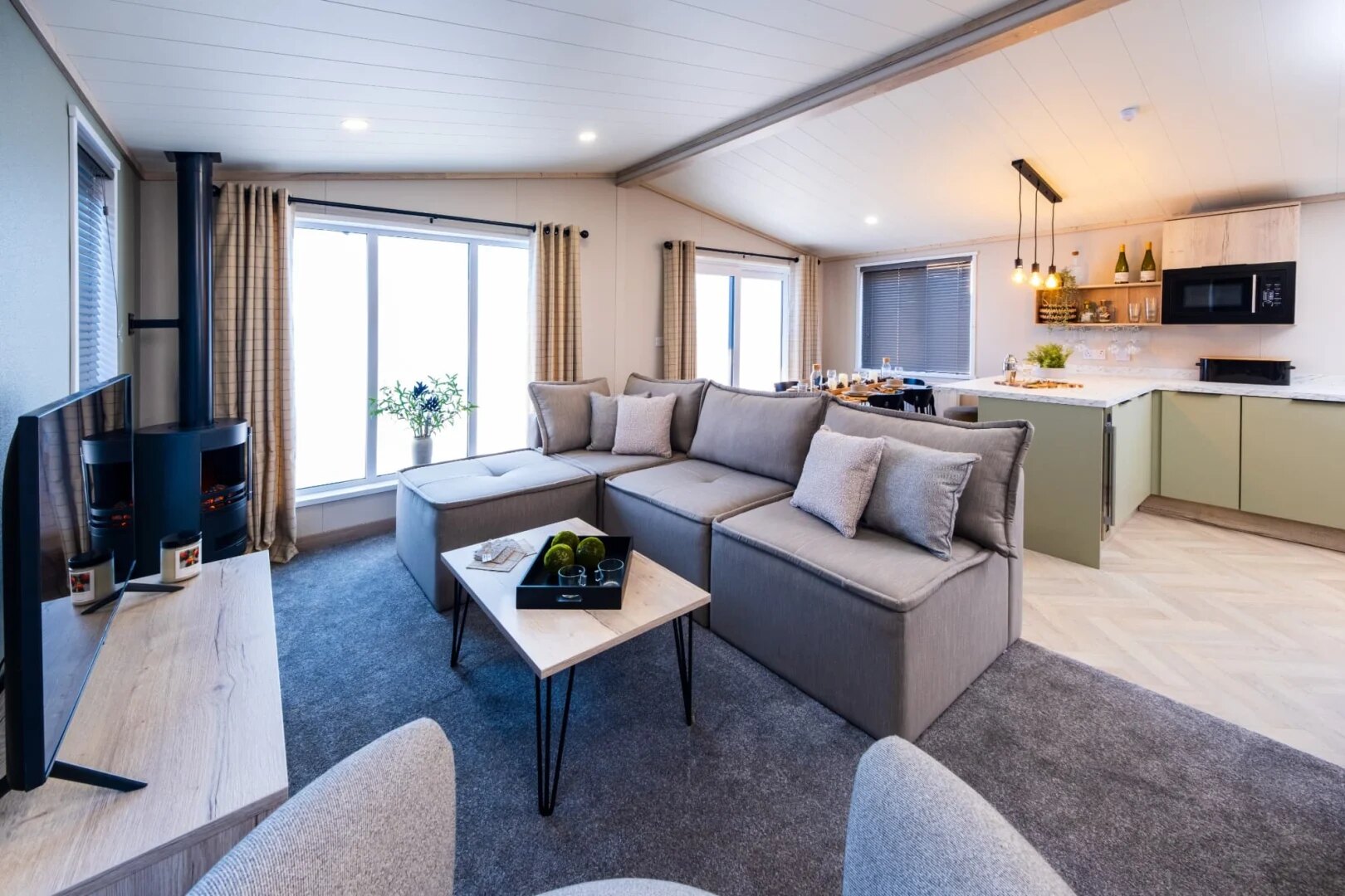An open-plan lodge living room with modular seating and a kitchen-diner beyond.