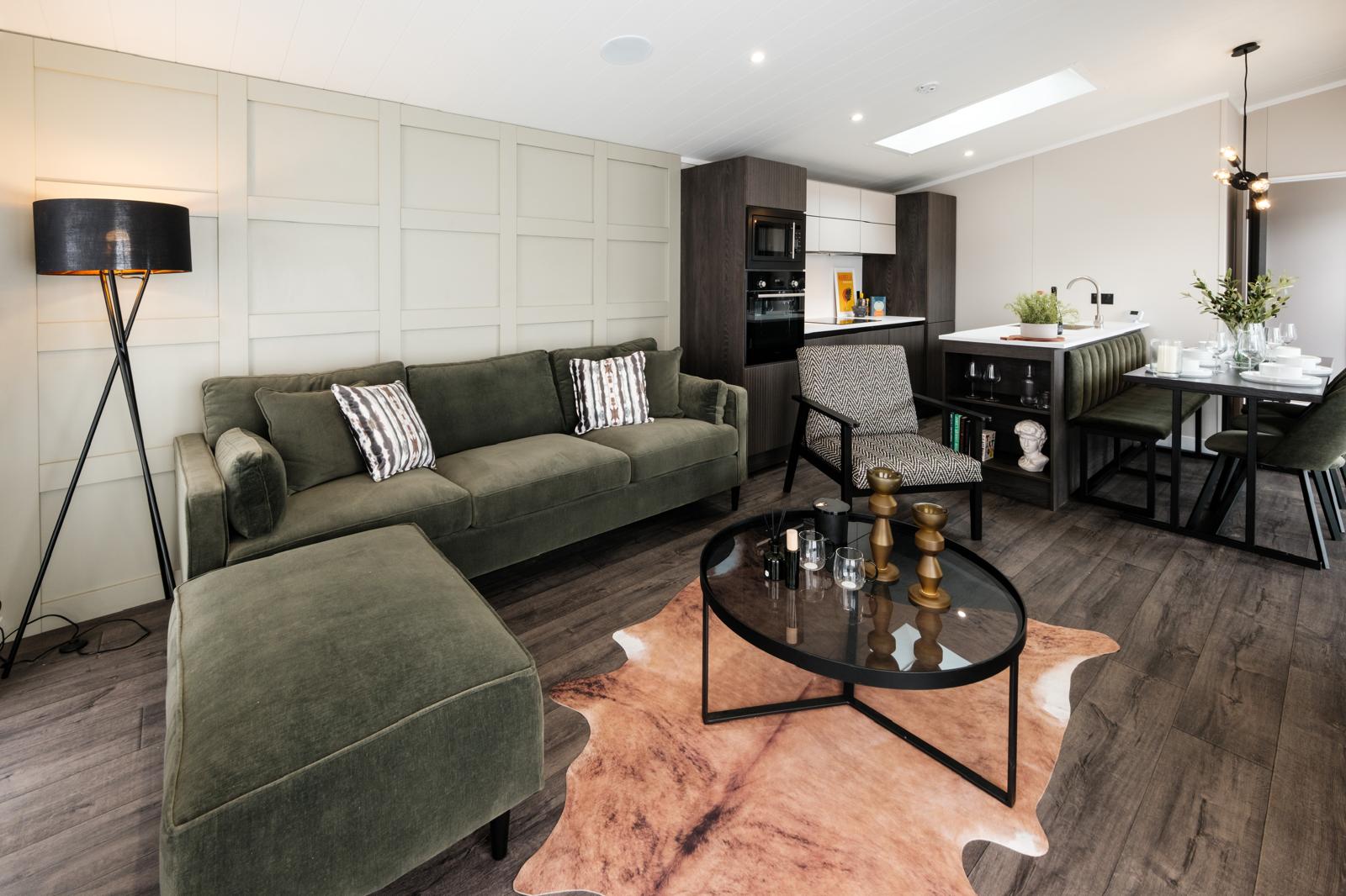 Living room with green velvet sofa opening onto the kitchen-diner.