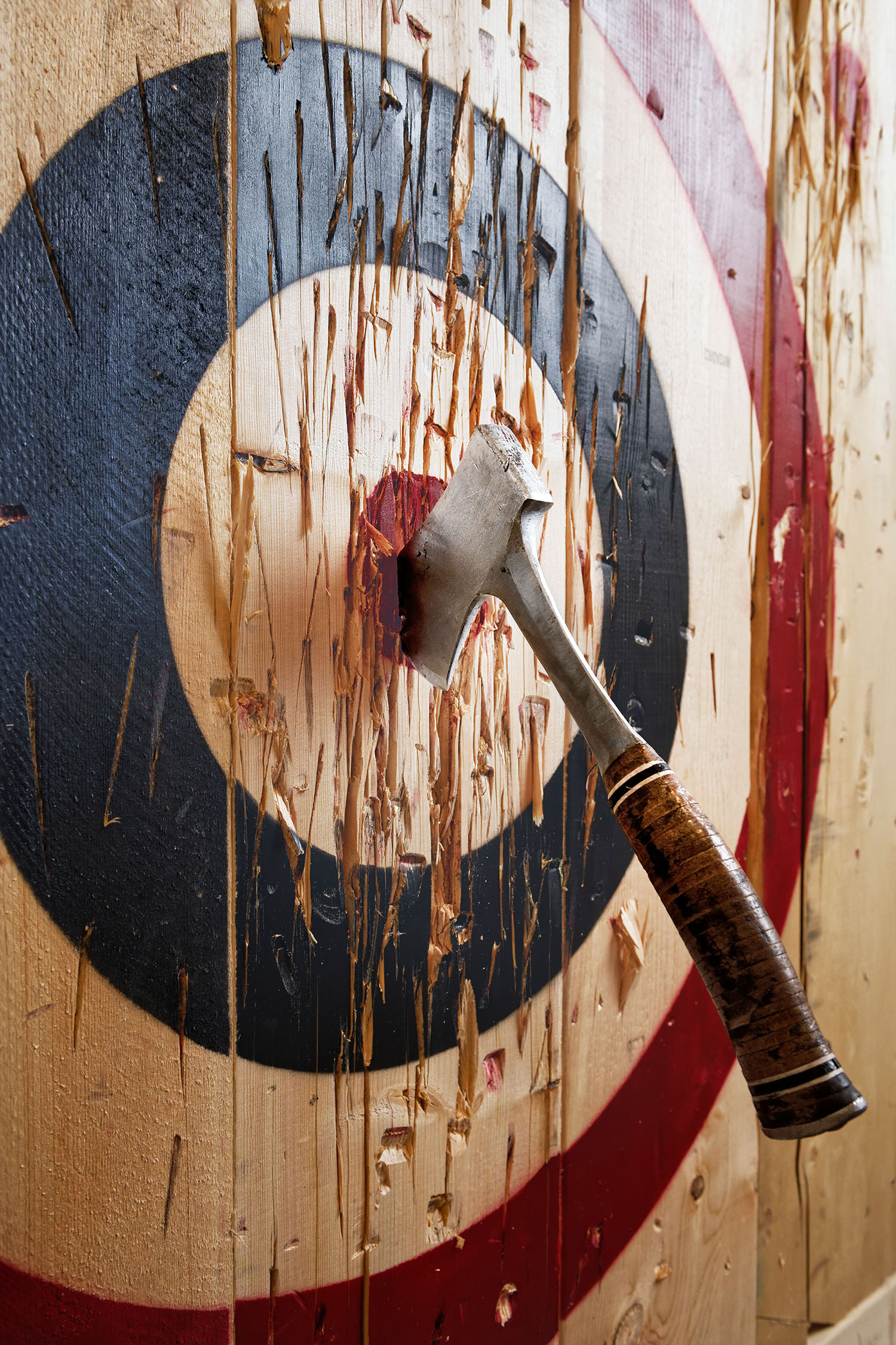 A throwing axe embedded in a wooden bullseye target.