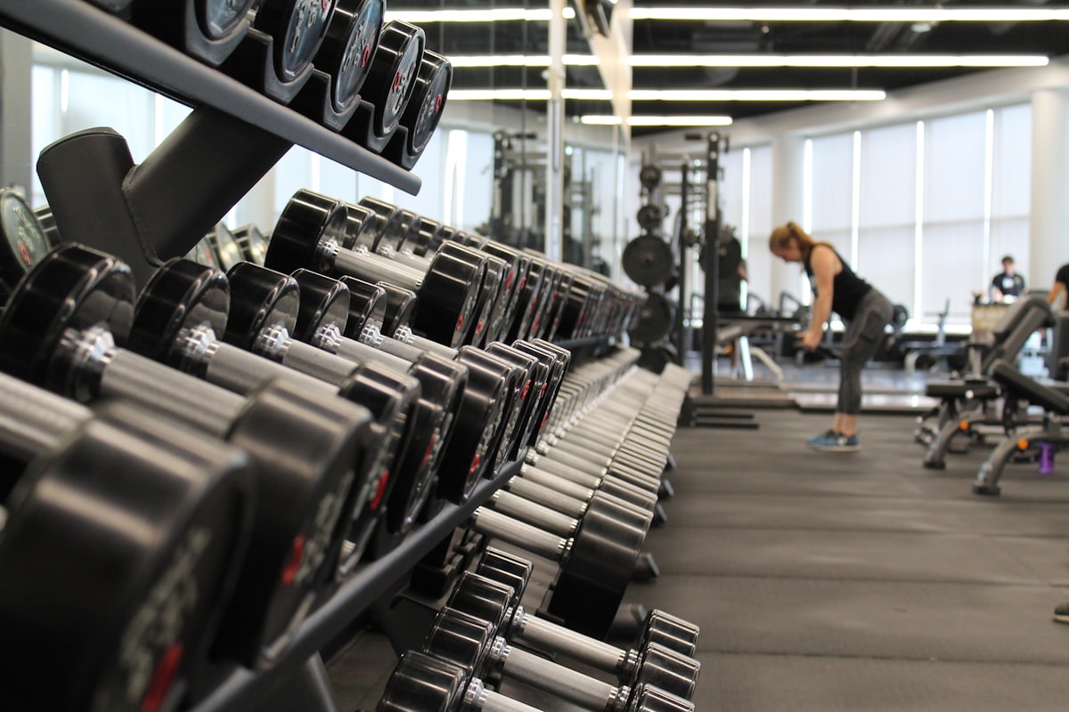 A modern gym with equipment and natural light, people training.