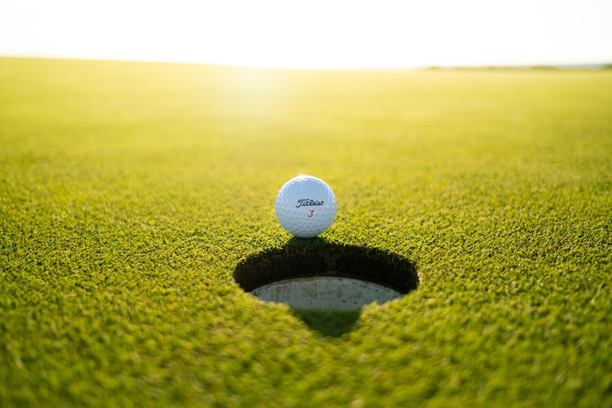 A putter striking a ball on a manicured adventure golf course.